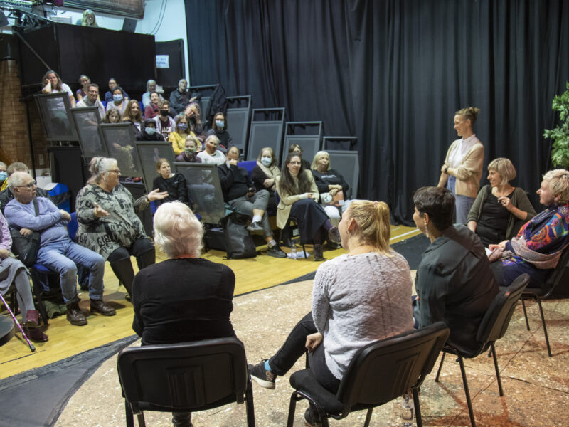 A panel of people sit on stage after a performance and answer questions from the audience