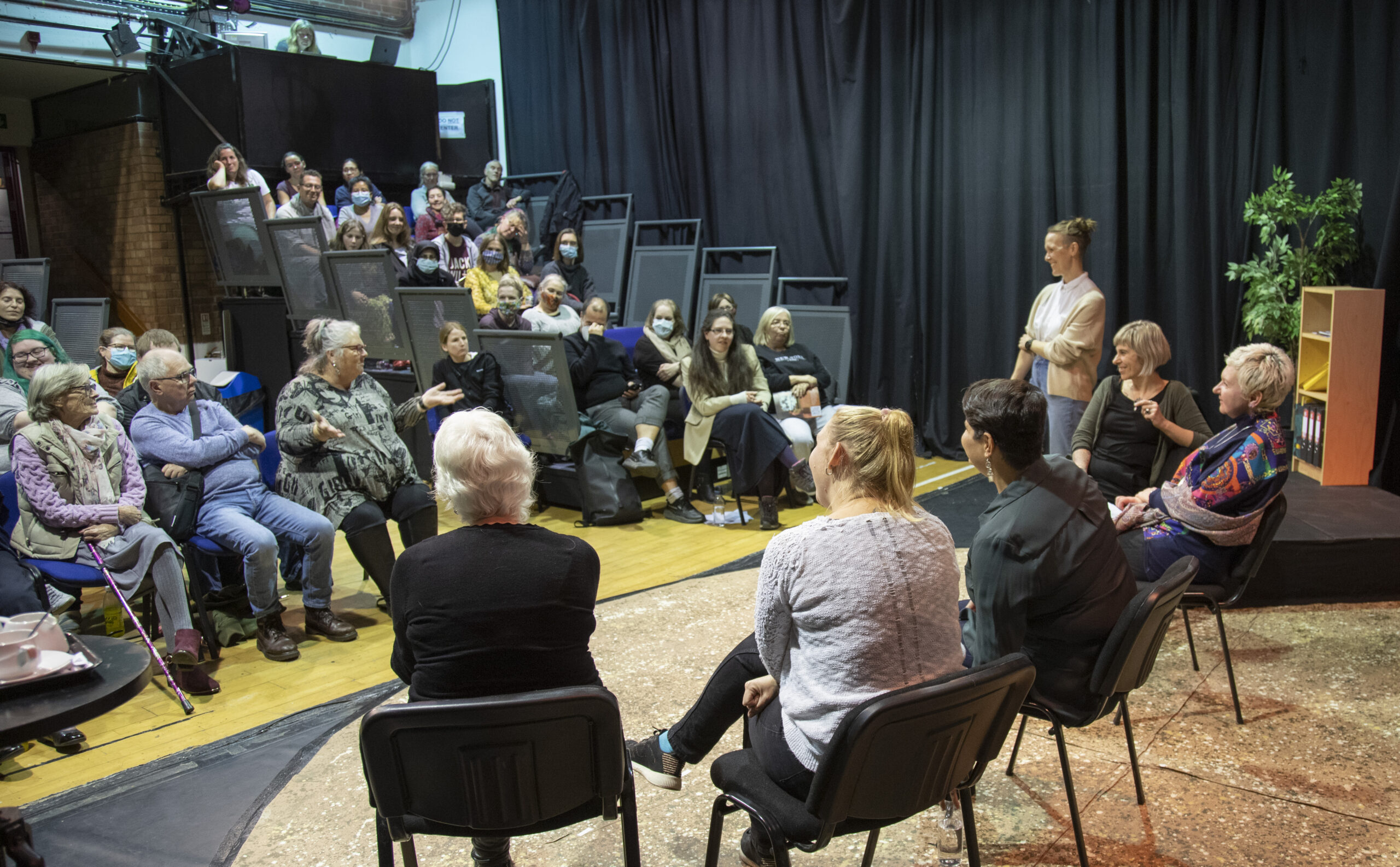 A panel of people sit on stage after a performance and answer questions from the audience