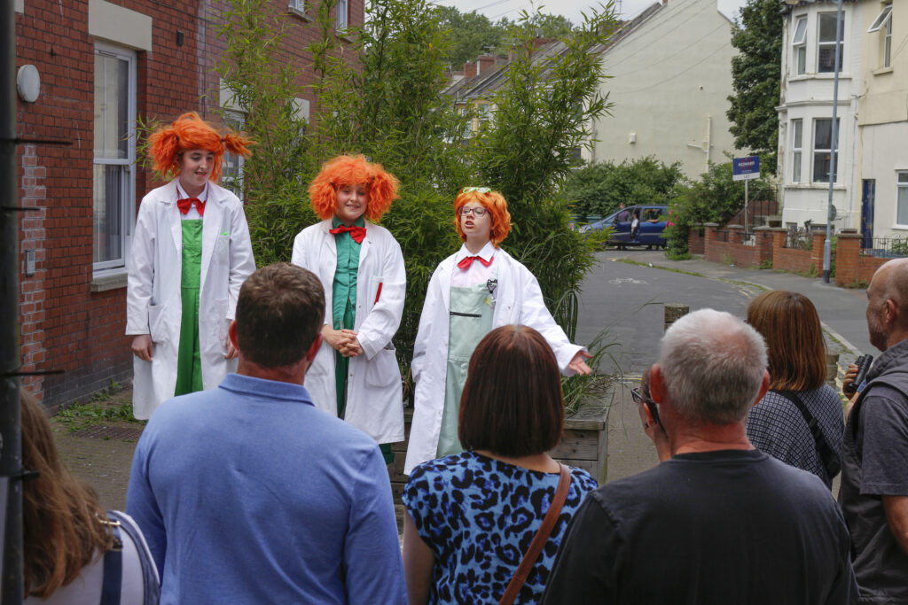 Three crazy scientists address an audience on East Street